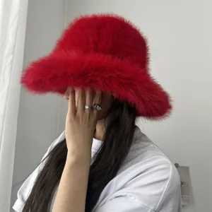 Détail d'un bob en fausse fourrure de renard rouge vif avec un large bord porté par un mannequin.