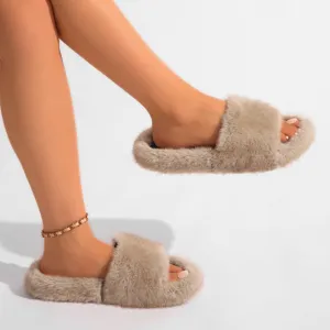 Gros plan de chaussons en fausse fourrure beige portés avec un bracelet de cheville doré