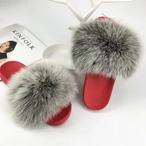 Dettaglio di ciabatte in pelliccia grigia con suole in PVC rosso antiscivolo di tendenza