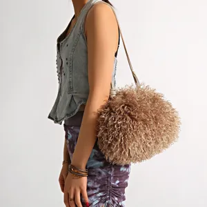 Model carrying a brown curly faux sheepskin cloud shoulder bag with long strap