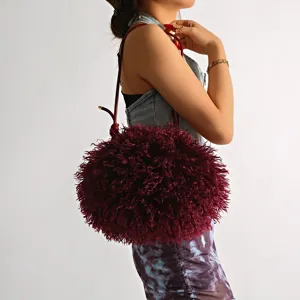 Detailed view of plush burgundy faux sheep fur cloud bag worn by a female model