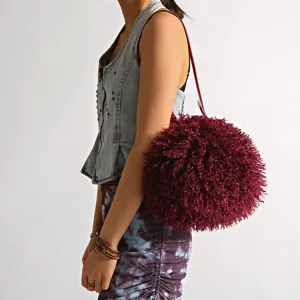 Large burgundy shaggy faux fur pom-pom shoulder bag styled on model for a trendy detail view