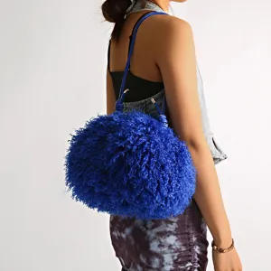 Stylish electric blue shaggy faux fur cloud bag shown as a shoulder bag on a model