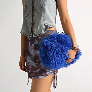 Detailed view of a vibrant blue fluffy faux fur cloud bag held by a stylish fashion model.