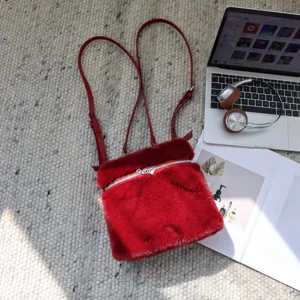 Hochwertiger roter Kunstfell-Rucksack auf einem Webteppich neben Laptop und Kopfhörern