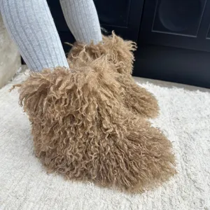 Gros plan de bottes de neige chaudes pour enfants en fausse fourrure bouclée marron.