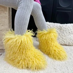 Gros plan sur des bottes en fausse fourrure jaune vif pour enfants sur tapis blanc