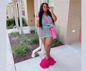Full body view of a model wearing fluffy pink Mongolian lamb fur slides outdoors