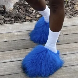 Close-up of bright blue Mongolian fur slides worn with white socks on a wooden deck.