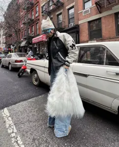 Detalle de estilo callejero de un bolso tote Y2K de piel sintética blanca con pelo largo suave