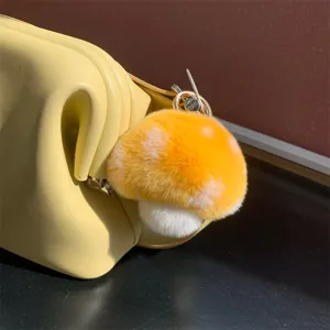 Close-up of a cute orange and white plush mushroom bag charm with fluffy texture