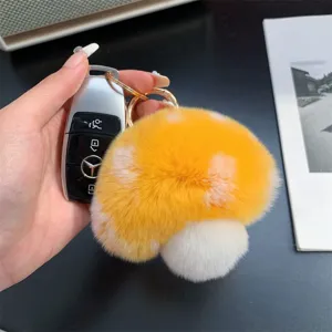 Soft yellow mushroom plush keychain held next to a car key for scale.