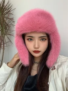 Detailed close-up view of pink faux fox fur ushanka hat worn by model for winter warmth