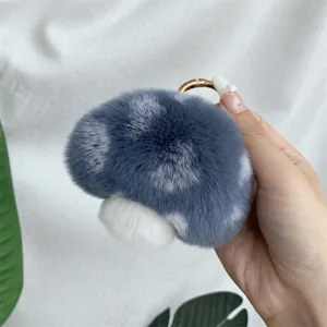 Close-up of a soft blue and white plush mushroom keychain with a gold metal ring accessory