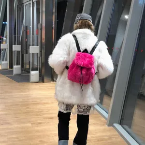 Rückansicht einer Person mit einem leuchtend rosa Plüschrucksack aus Kunstfell.