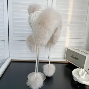Detalle de un gorro de punto blanco con ribete de piel de zorro y pompones