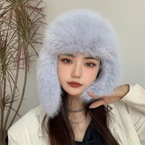 Model wearing a thick faux fox fur winter hat with plush ear flaps in light grey