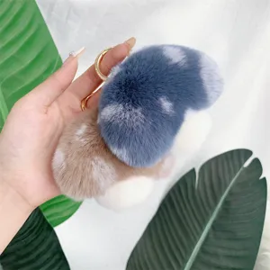 Close-up of soft mushroom plush charms in pastel blue and tan faux fur with gold ring