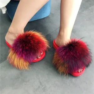 Dettaglio di pantofole in PVC rosso con pon pon in finta pelliccia multicolore