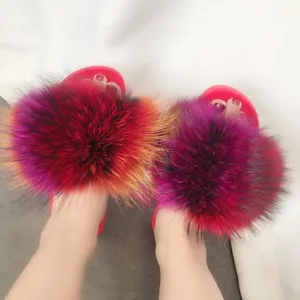 Dettaglio ravvicinato di ciabatte in pelliccia multicolore con suola in PVC rossa