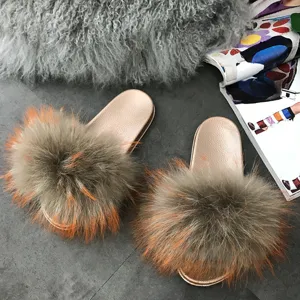 Fashionable golden PVC sole summer slippers featuring luxurious raccoon and fox fur pom poms