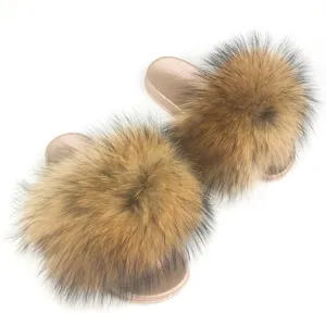 Stylish metallic gold PVC slides featuring luxurious fluffy raccoon fur pom-poms