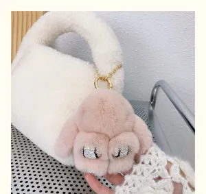 Vue détaillée d'un porte-clés lapin en peluche rose avec yeux en strass sur un sac blanc