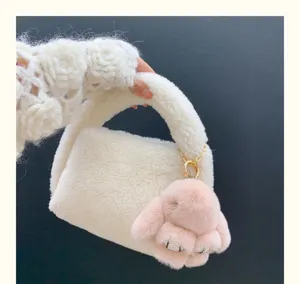 Détail d'un charme de lapin en peluche rose avec strass sur un sac à main blanc
