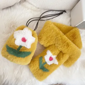 Close-up detail of yellow plush phone bag and scarf set featuring white flower embroidery
