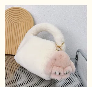 Détail d'un pendentif lapin en peluche rose avec des yeux en strass sur un sac blanc doux.