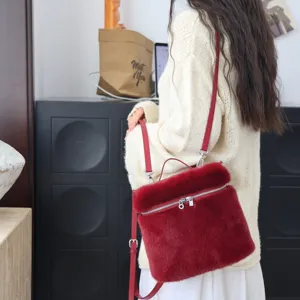 Nahaufnahme eines roten Kunstpelz-Rucksacks kombiniert mit einem cremefarbenen Pullover