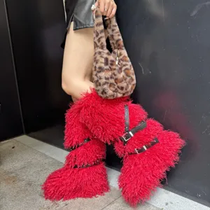 Gros plan de bottes en fausse fourrure rouge avec lanières cloutées noires et boucles en métal.