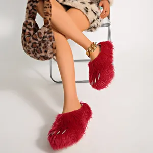 Close-up of fuzzy red monster claw slippers with realistic silver nails and thick soles.