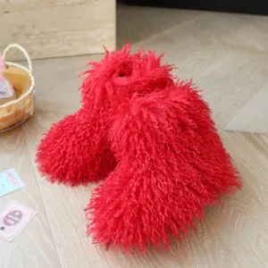 Vue détaillée de bottes de neige rouges en fausse fourrure pour enfants sur bois