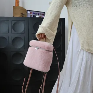 Detail des rosa Kunstpelz-Rucksacks, getragen von einem Modell in cremefarbenem Strick.