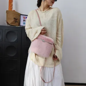 Detailaufnahme einer rosa Kunstfell-Umhängetasche kombiniert mit einem cremefarbenen Pullover