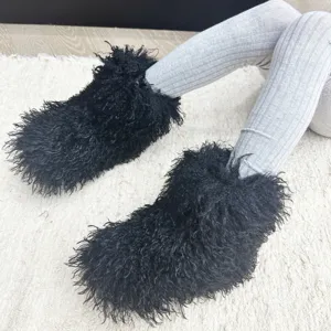 Détail macro de bottes en fausse fourrure noire pour enfants sur un tapis blanc texturé