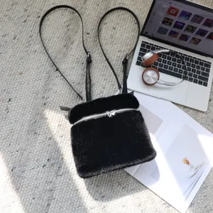 Lifestyle-Ansicht eines schwarzen Kunstpelz-Rucksacks auf einem gewebten Teppich.