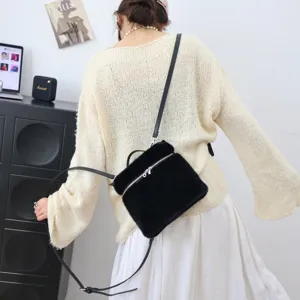 Nahaufnahme eines schwarzen Kunstfell-Rucksacks, getragen von einem Modell im Strickpullover.