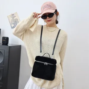 Model trägt eine weiche schwarze Kunstpelzhandtasche mit Reißverschluss und Trägern