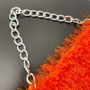 Close-up detail of an orange faux fur baguette bag with a polished silver chain strap