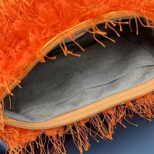 Detail of vibrant orange plush handbag featuring grey suede lining and zipper closure