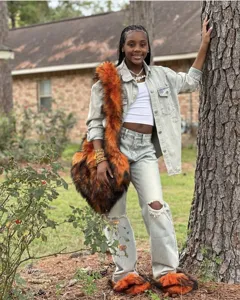 Junges Model trägt orangefarbene Fuchspelz-Imitat Hausschuhe im Y2K-Stil mit großer Tasche