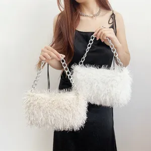 Detail view of two white and beige fuzzy faux fur underarm bags with chunky silver chains.
