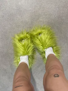 Gros plan de claquettes en fausse fourrure vert citron portées avec des chaussettes.