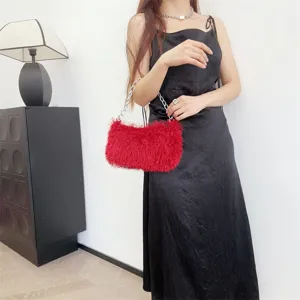 Model holding a vibrant red faux fur chain baguette bag against a black dress