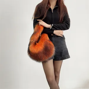 Detail shot of a plush faux raccoon fur handbag in orange gradient worn by a model