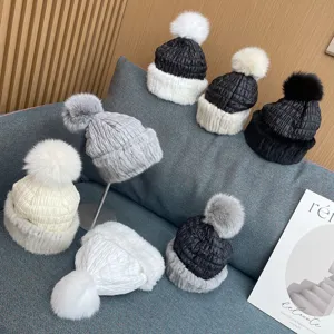 Macro view of various winter fur hats with fox fur pom-poms on a sofa