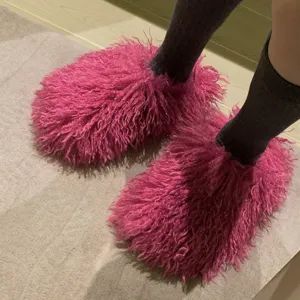 Close-up of vibrant pink Mongolian fur slides on person wearing dark grey socks