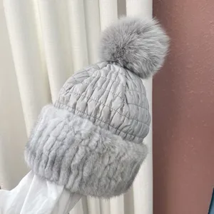 Close-up of grey thermal winter hat with large fur pom-pom and mink trim details
